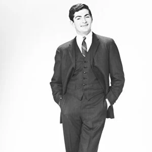 Elegant man with hands in pockets posing in studio, (B&W), portrait