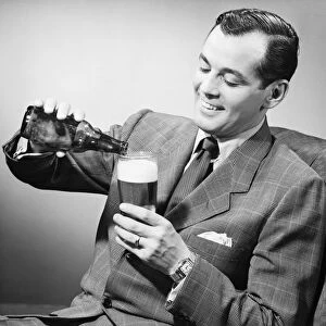 Elegant man pouring beer from bottle into glass, (B&W)