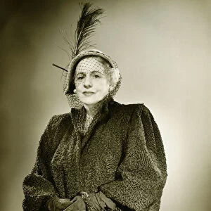 Elegant mature woman in hat and coat posing in studio, (B&W), (Portrait)