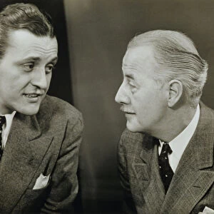 Two elegant men talking in studio, (B&W), close-up