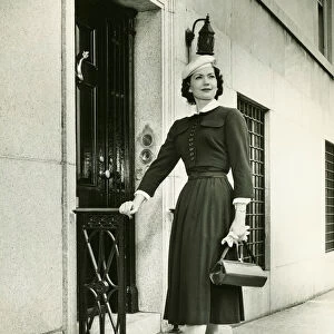 Elegant woman posing at building entrance, (B&W), portrait