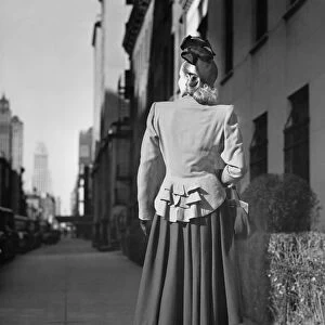 Elegant woman standing alone on sidewalk, Rear view, (B&W)