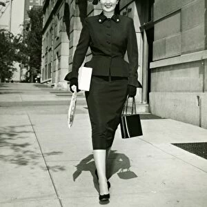 Elegant woman walking on sidewalk, (B&W)