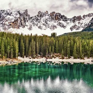 The emerald green Lake Carezza reflects the trees in the western Dolomite mountains of northern Italy The emerald green Lake Carezza reflects the trees in the western Dolomite mountains of northern Italy