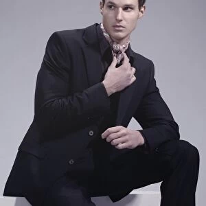 Fashion shot of a young man wearing a suit, sitting