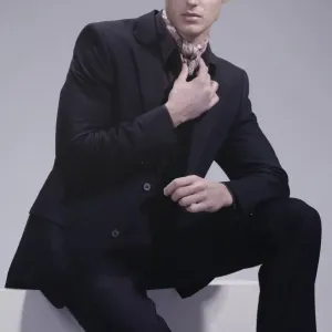 Fashion shot of a young man wearing a suit, sitting