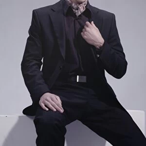 Fashion shot of a young man wearing a suit, sitting