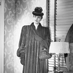Fashionable woman in mink coat and hat standing in anteroom, (B&W), portrait