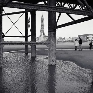 Père avec enfants (10-13) sur la plage, vue à travers les supports de la jetée. Père avec enfants (10-13) sur la plage, vue à travers les supports de la jetée.