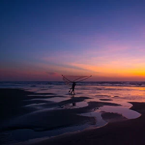 Fisherman walking on the beach at dawn in Vietnam