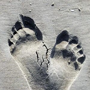 Two footprints in the sand on a beach