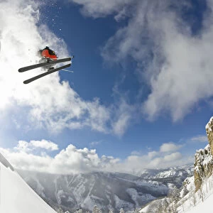 Freestyle skier spinning while jumping off of cliff