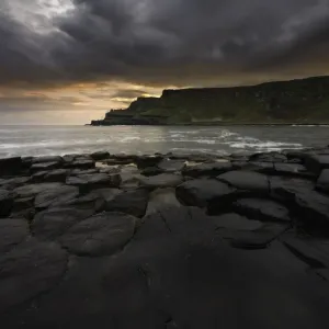 Giants Causeway on moody morning with colorful sunrise Giants Causeway on moody morning with colorful sunrise