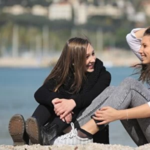 Two girlfriends, teenagers, sitting on the beach, Menton, Alpes-Maritimes, Provence Alpes, France