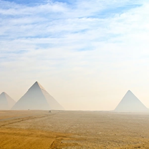 The Giza pyramids viewed from distance in morning haze and blue skies