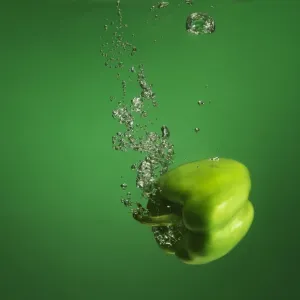 green pebber fruit splashed into water green pebber fruit splashed into water