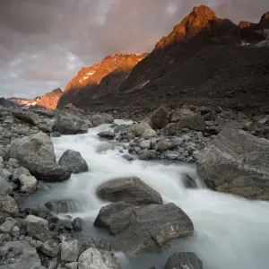 Greenland, Itilleq, setting sun lighting mountain peaks above mountain stream along Itilleq Fjord Greenland, Itilleq, setting sun lighting mountain peaks above mountain stream along Itilleq Fjord