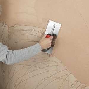 Hand applying plaster to a wall with a trowel