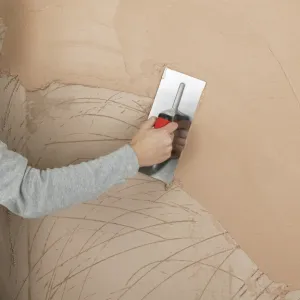 Hand applying plaster to a wall with a trowel