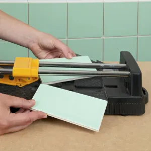 Hand holding tile in tile cutter