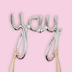 Hands holding a silver "YAY" balloon print Hands holding a silver "YAY" balloon print