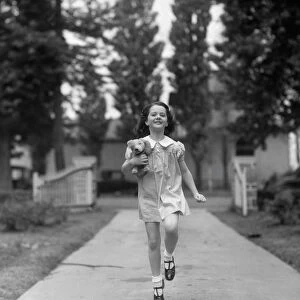 Happy, carefree girl running down sidewalk, holding stuffed animal under arm