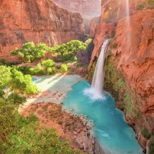 Havasu Falls in Arizona plunges in turquoise waters as the sun rises above the cliffside