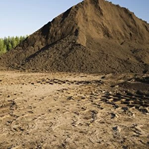 Heavy tire tracks and a mound of topsoil in a commercial sandpit, Quebec, Canada