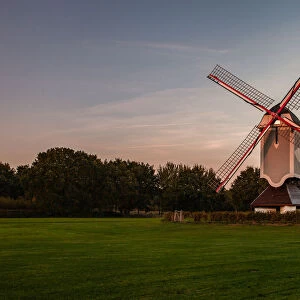 A historic windmill at sunset with a bench