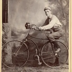 Historical cabinet card portrait of teenage boy on bike in studio