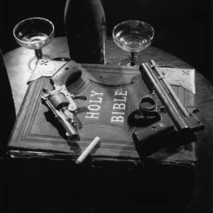 Humo Sagrado; Dos pistolas de mano y un cigarrillo sobre una copia de la Biblia Santa en una producción de la obra del teatro de Edgar Wallaces On The Spot. Humo Sagrado; Dos pistolas de mano y un cigarrillo sobre una copia de la Biblia Santa en una producción de la obra del teatro de Edgar Wallaces On The Spot.