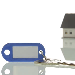 Key lying in front of a miniature house, symbolic image for property market