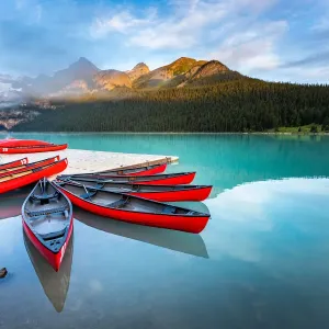 Lake Louise, canoe and kayak on calm water at sunrise. Banff, Canadian Rockies, Canada Lake Louise, canoe and kayak on calm water at sunrise. Banff, Canadian Rockies, Canada