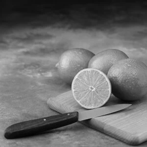 Lemon whole and half cut on chopping board with knife