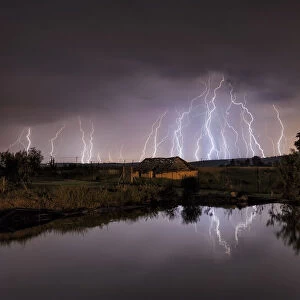 Lightning strikes over abandoned farm house and dam, Magaliesburg, Gauteng Province, South Africa