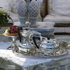 Luxuriously set coffee table with silver coffee and tea pots, and a fruit pie on a silver cake plate