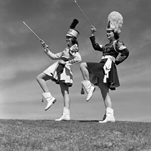 Two majorettes in uniform doing routine with batons