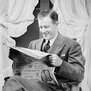 Man reading newspaper in living room, (B&W)