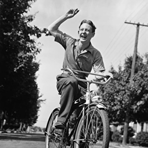 Man riding bicycle, waving, (B&W)