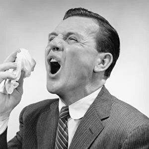 Man sneezing, posing in studio, (B&W), close-up