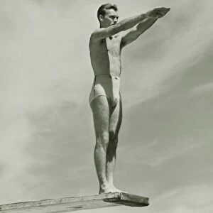 Man on springboard ready to jump, (B&W), low angle view