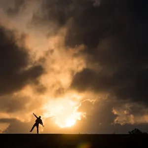 One man standing in causeway over cloudy sunset