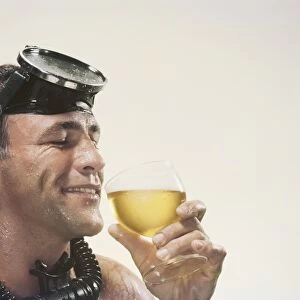 Man wearing snorkel holding wine glass, smiling