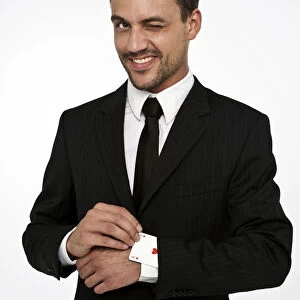 Man wearing a suit pulling an ace of hearts out of his sleeve