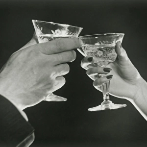 Man and woman toasting martini glasses, close up of hands