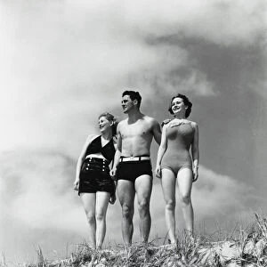 Man and two women standing on beach sand dune
