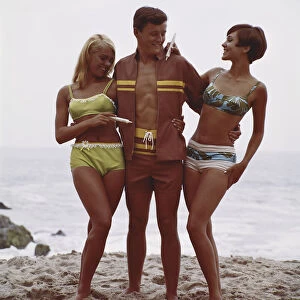 Man with two women standing on beach, smiling