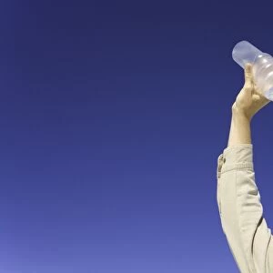 Mature man pouring water over face under clear sky, low angle view
