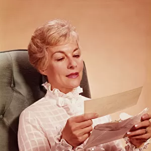 Mature woman sitting in chair, reading letter. (Photo by H. Armstrong Roberts / Retrofile / Getty Images)