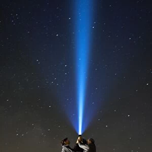 Men with his close hands illuminating the night sky with a bundle of light